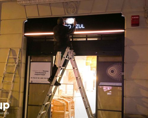 10 operario instalando rotulo maro azul ingrup estudi diseno construccion retail granollers barcelona